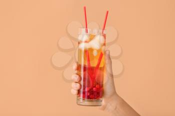 Female hand with cold tea in glass on color background�