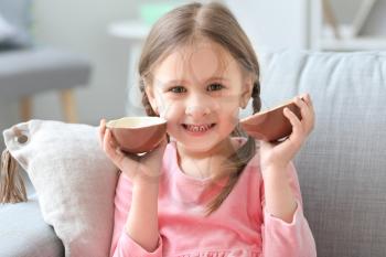Cute little girl with sweet chocolate egg at home�