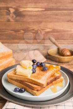 Tasty toasted bread with honey, butter and fruits on plate�