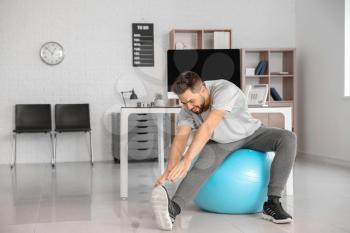 Man doing exercises with fitness ball in office�