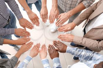 Group of people putting hands together indoors, top view. Unity concept�