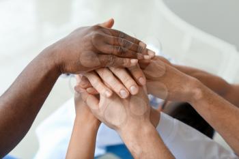 Group of people putting hands together indoors. Unity concept�