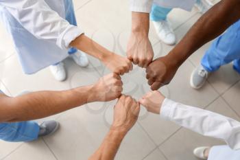 Group of doctors putting hands together in clinic, top view. Unity concept�