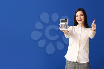 Young woman with calculator showing thumb-up on color background�