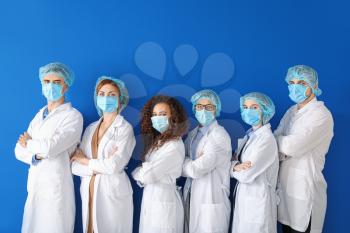 Group of doctors with protective masks on color background. Concept of epidemic�