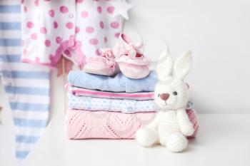 Baby clothes with booties and toy on table in room�