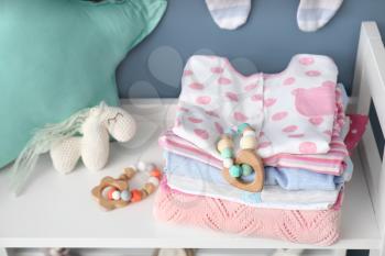 Baby clothes and toys on shelf in room�