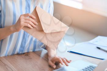 Young woman with laptop and letters in office�