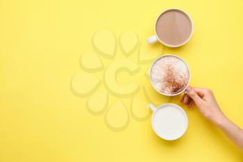Female hand with cups of coffee on color background�