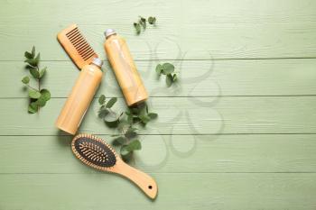 Shampoo with herbal extract, comb and brush on wooden background�