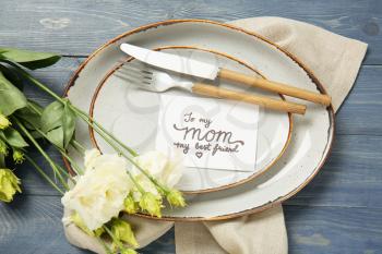 Table setting with card for Mother's day dinner on color wooden background�