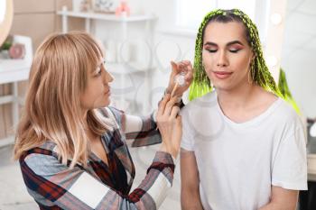 Makeup artist working with transgender woman at home�