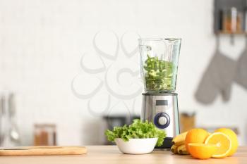 Modern blender with fresh fruits and vegetables on table in kitchen�