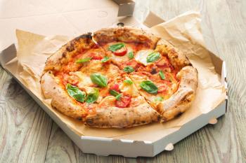 Cardboard box with delicious pizza Margherita on wooden background�