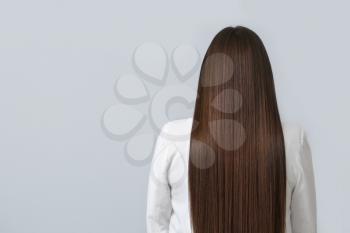 Young woman with beautiful straight hair on grey background 
