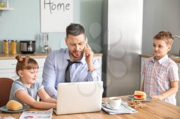 Little children keeping father from his work at home�
