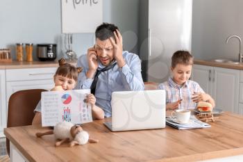 Little children keeping father from his work at home�