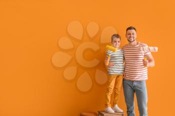 Little son helping his father to paint wall at home�