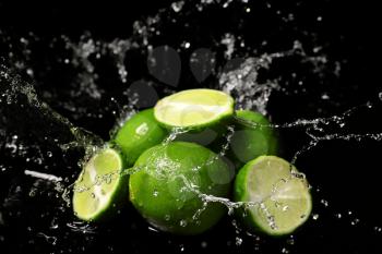 Fresh limes with water splashes on dark background�
