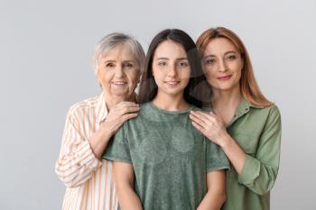 Portrait of mature woman with her adult daughter and mother on grey background�
