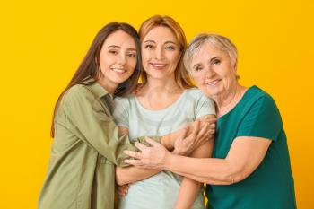 Portrait of mature woman with her adult daughter and mother on color background�