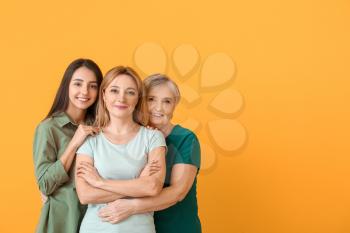 Portrait of mature woman with her adult daughter and mother on color background�