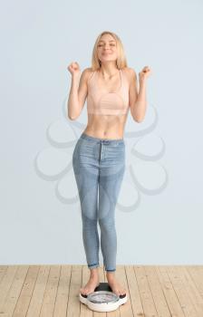 Happy slim woman with scales on color background. Weight loss concept�