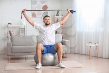 Sporty young man training at home�
