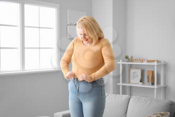 Troubled overweight woman in tight clothes at home�
