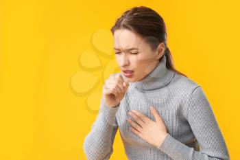 Ill coughing young woman on color background�