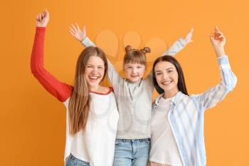 Happy lesbian couple with little adopted girl on color background�