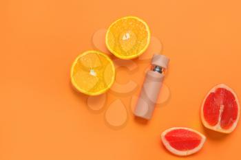 Bottle of perfume with citrus fruits on color background�
