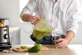 Man pouring healthy smoothie in glass at home�