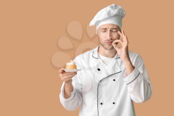 Male confectioner with tasty dessert on color background�