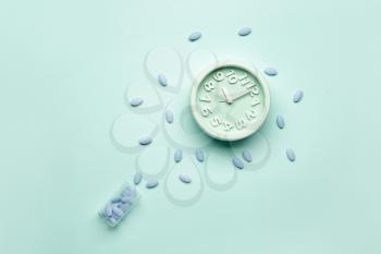Alarm clock and sleeping pills on color background�