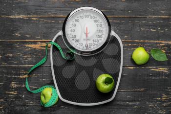 Weight scales with measuring tape and apples on wooden background. Slimming concept�