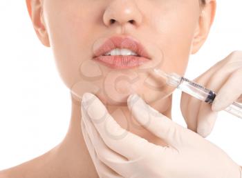 Young woman receiving filler injection on white background�