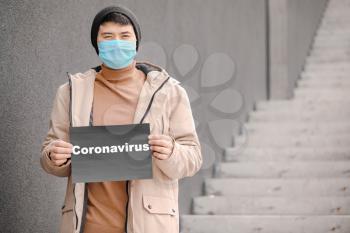 Asian man wearing protective mask on city street. Concept of Coronavirus epidemic�