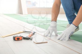 Carpenter installing laminate flooring in room�