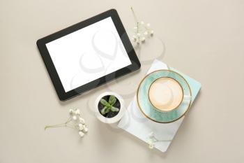 Cup of coffee, notebook, tablet PC and flowers on light background�