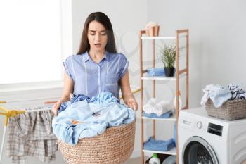 Displeased young woman doing laundry at home�