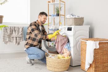 Displeased man doing laundry at home�