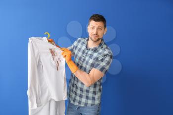 Displeased man with dirty clothes on color background�
