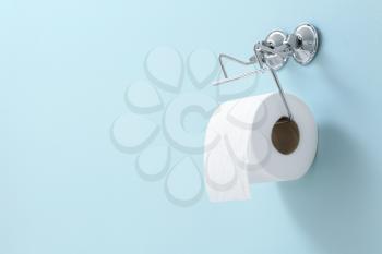 Holder with roll of toilet paper hanging on wall�