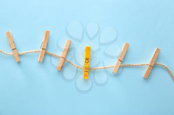 Clothes pegs with drawn smile on color background�