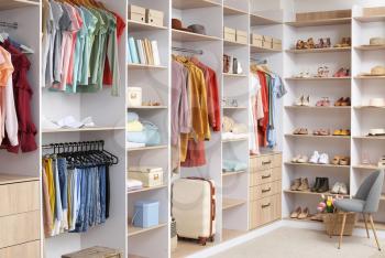 Big wardrobe with different clothes and accessories in dressing room�