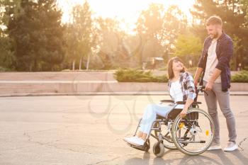 Young woman in wheelchair and her husband outdoors�