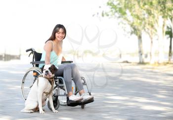 Young woman in wheelchair and her service dog outdoors 