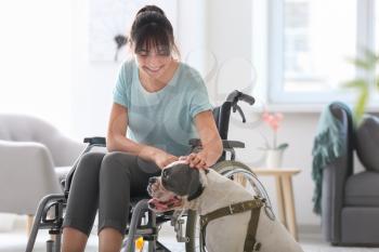 Young woman in wheelchair with service dog at home�