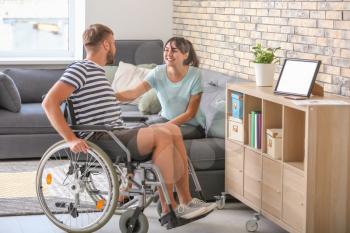 Young man in wheelchair and his wife at home�